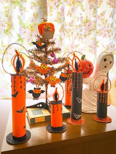 an assortment of halloween decorations on a table in front of a window with drapes