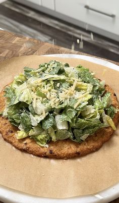 a pizza with lettuce on it sitting on top of a white platter