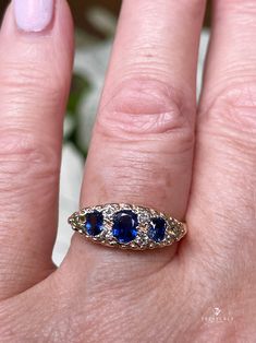 a woman's hand holding a ring with two blue stones on top of it