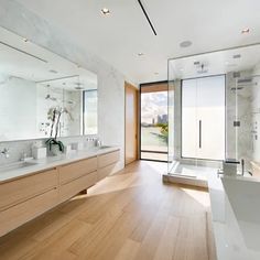 a large bathroom with two sinks and mirrors on the wall, along with a walk in shower