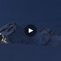 a man riding skis down the side of a snow covered mountain under a blue sky