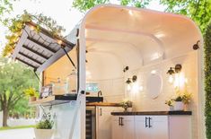 an outdoor kitchen with potted plants on the counter and cupboards in the back