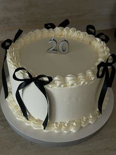 a white cake with black ribbons and the number 20 on it