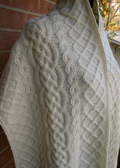 a white knitted shawl draped over a brick wall