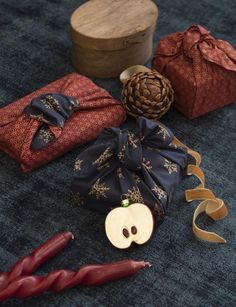 an apple and other items are laying on the floor next to some ribbons, pine cones, and a wooden box