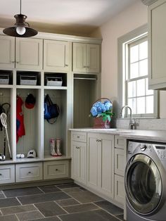 a washer and dryer in a small room with cabinets on either side of the sink