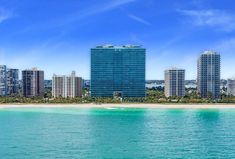 the city is next to the beach in the middle of the ocean and blue sky