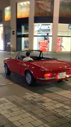 a red convertible car parked in front of a building