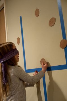 a girl is painting the wall with blue tape and some circles on it in an empty room