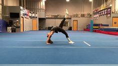 a man is doing a handstand on a blue floor in an indoor gym