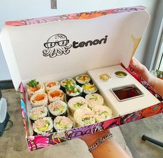 a person holding a box filled with sushi