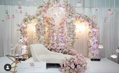 a white couch sitting in front of a flower covered wall with pink and white flowers