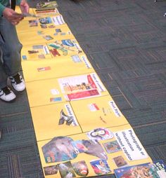 a person sitting on the floor next to a long table covered in pictures and books