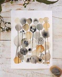 a watercolor painting of flowers and leaves on a white wooden background with two spoons next to it