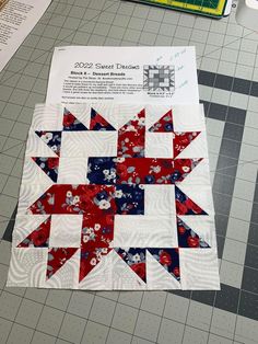 a red, white and blue quilt is laying on the floor next to some scissors