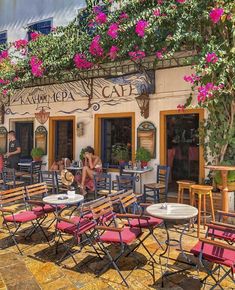 there are many tables and chairs in front of the building with pink flowers on it