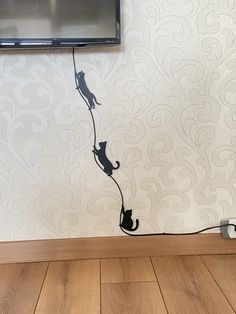 a television mounted to the side of a wall next to a cat on a string