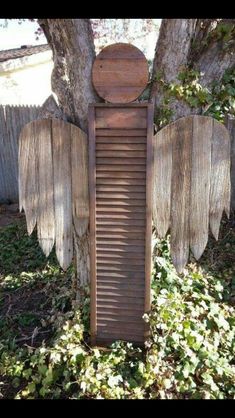 an angel's wing is sitting in the grass next to a tree and fence