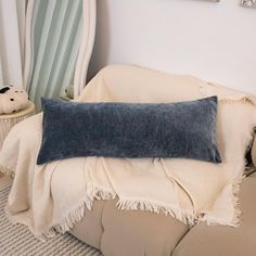 a blue pillow sitting on top of a white couch next to a stuffed teddy bear