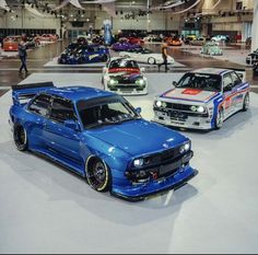 three cars on display at an auto show, one is blue and the other is white