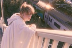 a young man standing on top of a balcony next to a train