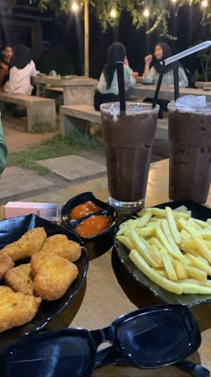 three plates of food on a table with two drinks and some other foods in front of them