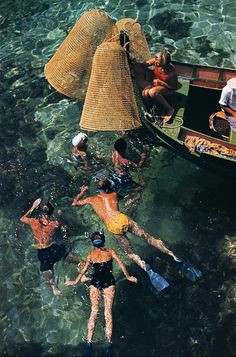 several people are floating in the water on their own boats and some have hats over their heads