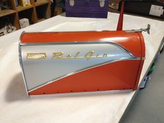 an orange and silver mailbox sitting on top of a white tablecloth covered table