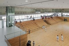 several people are standing in the middle of a large room with wooden floors and white walls