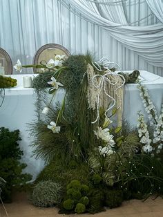 an arrangement of flowers and greenery on the ground at a wedding reception with white draping