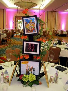 a table with pictures and flowers on it in a room decorated for a wedding or other function