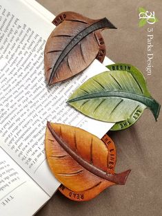 three leaf magnets sitting on top of an open book