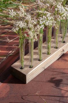 several vases filled with baby's breath flowers sitting on a wooden shelf outside