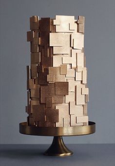 a cake that has been made out of wooden blocks on a metal stand with a gray background