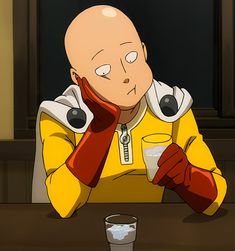 a bald man sitting at a table with a glass in front of him