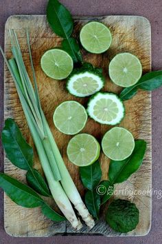 limes, celery, and onions on a cutting board with green leaves