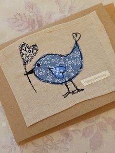 a small blue bird with a heart on it's head sitting on top of a piece of paper