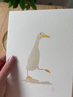 a person holding up a card with a bird on it's back and watercolor paint