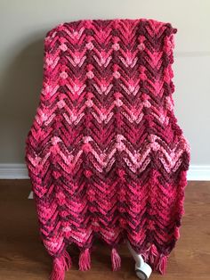 a red and pink blanket sitting on top of a wooden floor next to a wall