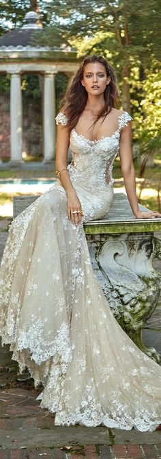 a woman in a wedding dress sitting on a stone bench with her hand on her hip