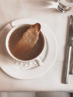 a white plate topped with soup and a piece of bread