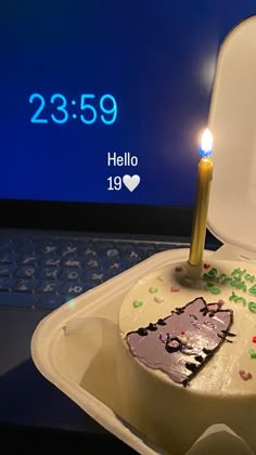 a birthday cake with a lit candle on it sitting in front of a laptop computer