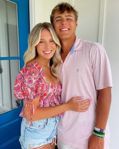 a man and woman standing next to each other in front of a blue door smiling