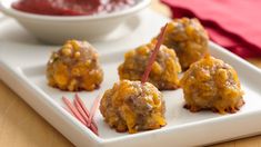 some meatballs are on a white plate with red skewers next to it