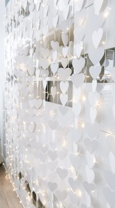 a white wall with hearts on it and string lights hanging from the ceiling behind it