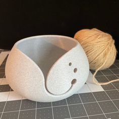 a ball of yarn is next to a bowl with a smiley face on the side