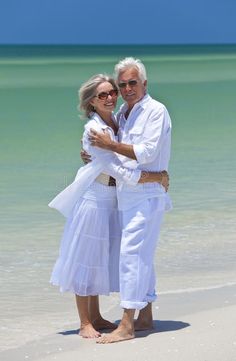 an older couple hugging on the beach in front of the ocean royalty images and stock photos