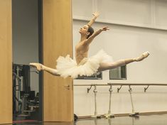 a young ballerina is performing on the floor