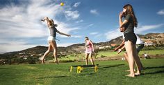 three girls are playing frisbee in the grass