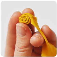 a person holding a tiny yellow flower in their hand